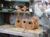 The necks will be attached to the bodies on this table. The ukulele on the left has a fretboard attached to the neck and the bridge attached to the body.